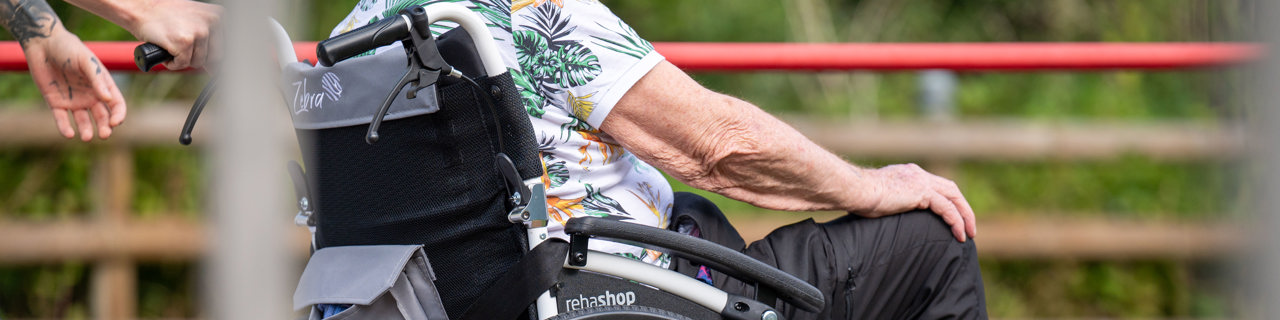 Parkinsonpatientin im Rollstuhl zusammen mit der Pflege im Park der Rehaklinik Zihlschlacht