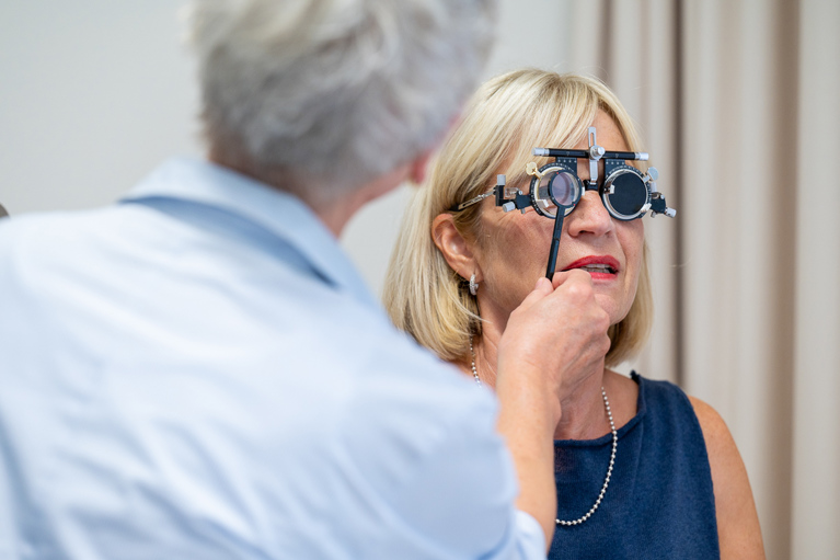 Neurologische Rehabilitations-Patientin bei der Vermessung der Sehstärke in der Orthoptik